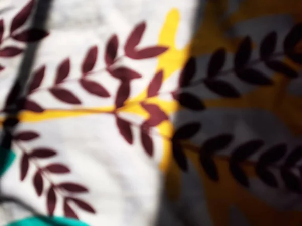 Blurred or unfocused or defocused sunlight and shadow on floral textile bed