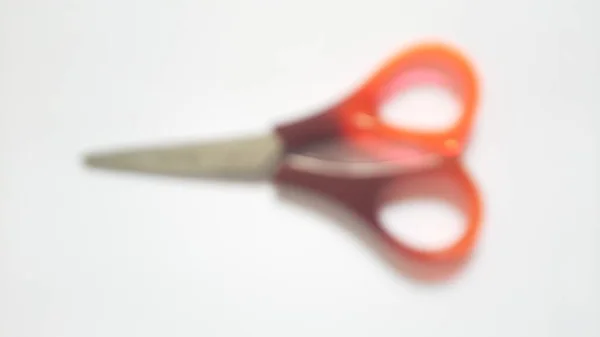 Blurred or unfocused or defocused single or one red orange brown scissors on isolated white background
