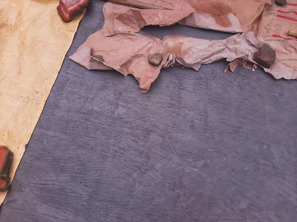 Roof tile on wet cement floor covered by white plastic bag and tarpaulin