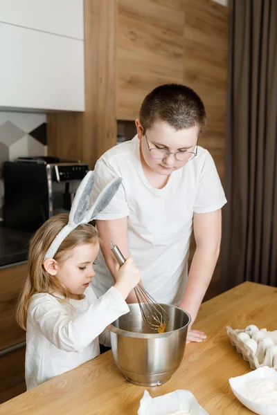 Brat Uczy Siostrzanej Kuchni Dziecko Miesza Ciasto Króliczych Uszach Kuchni — Zdjęcie stockowe