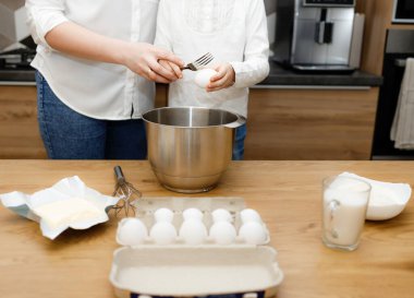 Anne kızına yumurta kırmayı, yumurta çırpmayı modern mutfakta hamuru hazırlayıp karıştırmayı öğretiyor. Küçük yardımcı. Birlikte olmaktan keyif alıyorum. Aile aktivitesi. Aletsiz zaman