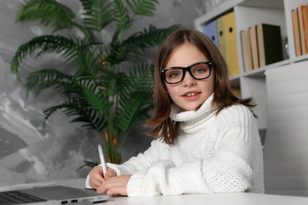 Criança Morena Óculos Sentado Escrevendo Perto Laptop Mesa Branca Miúdo — Fotografia de Stock