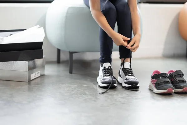 Çocuğun belirsiz yüzü, ayakkabı bağcıklarını bağlayan elleri ve mağazada spor ayakkabıları denemesi. Alışveriş merkezinde alışveriş, mevsimlik satış konsepti. Boşluğu kopyala