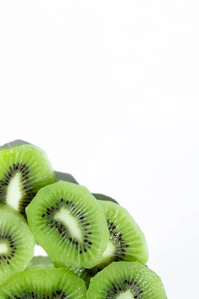 Beyaz dikey arkaplan köşesinde dilimlenmiş kivi, metin için boşluk