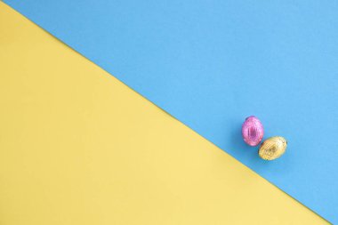Çapraz sarı ve mavi arka planda pembe ve altın renkli Paskalya yumurtalarının üst görüntüsü. Mutlu Paskalya Konsepti, tasarım için yer