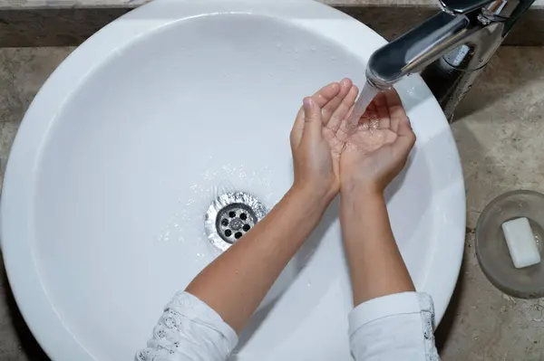 Çocuk tuvalette ellerini yıkıyor, tuvaletin üst katında. Hijyen ve bakım konsepti