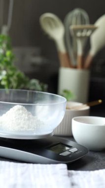 Kadınlar mutfak terazisinde kaşıkla su dökerler. Ekmek pişirmek, ekmek yapmak, hamur mayası hazırlamak, evde pişirmek için gerekli malzemeleri tartmak.