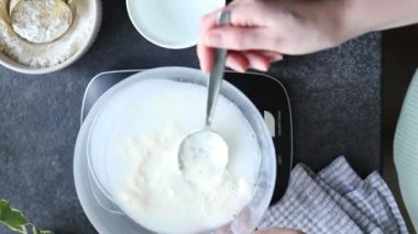 Ekşi ekmek pişirmek, mayalı ekmek hazırlamak ya da evde hamur mayası hazırlamak için mayalı mayalı mayalı marşları karıştıran kadın ellerinin üst görüntüsü. Mutfak ölçeği, mutfak tezgahında kaşık ve bardak ölçümü.