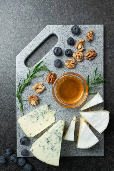 Aperatifler - Brie, camembert, ballı, biberiyeli, beyaz ve mavi küflü yumuşak peynirli taş kesme tahtası. Üst görünüm