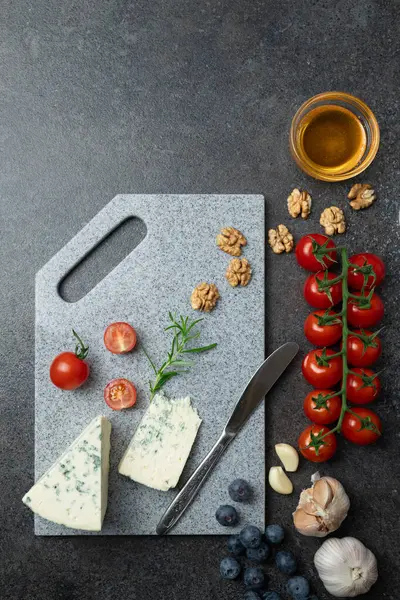 Aperatifler - küflü yumuşak peynir, bal, biberiye, kiraz domatesleri ve sarımsak, taştan kesilmiş yabanmersini. Üst görünüm, alanı kopyala