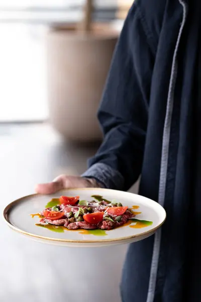Restoran garsonu yemek getiriyor. Ayakta duran ve tabağı yemek için hazır tutan kişi