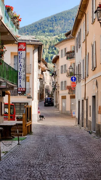 Stock image A narrow street in the north of Italy (Bormio) with beautiful european architecture. In the background you can see a mountainous landscape. The old road is made of cobblestones.