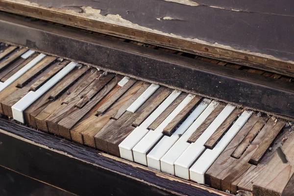 Old broken piano. Keyboard with broken, peeled piano keys.