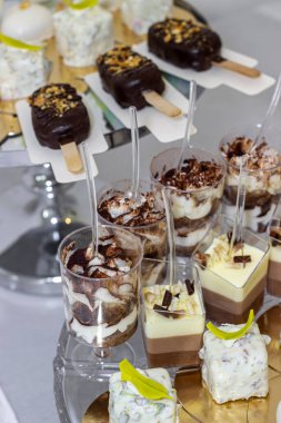 Düğün çikolatası. Tatlı meyveli tatlılarla dolu bir masa. Beyaz çikolatalı kalpler, çilekli tatlılar, fıstıklı pasta, tiramisu, çikolatalı dondurma. Düğün, parti, doğum günü için güzel bir masa. 