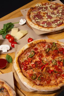 Ahşap bir masada farklı pişmiş pizzalar. Restoran menüsü, pizza. Çeşitli pizza çeşitleri..