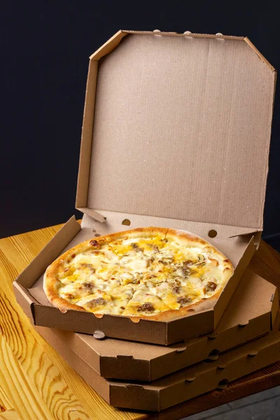 pizza in an open cardboard box. Pizzeria, restaurant menu. Vertical, dark background.