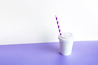 Plastic Coffee glass with a straw on a lilac background