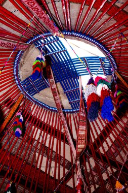 İçerideki geleneksel Kazak yurdunun üst kısmı renkli püsküllerle süslenmiş. Göçebeler Evi. 