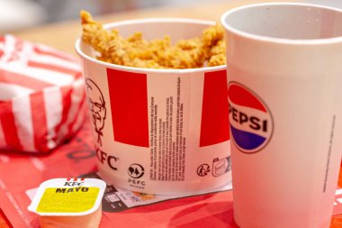 Padova, İtalya - 15 Nisan 2025 KFC fast food restoranı Strip kova, burger, Pepsi, sos. Karanlık bir arka planda fast food. Daha fazla atık imhası hakkında logolar. 