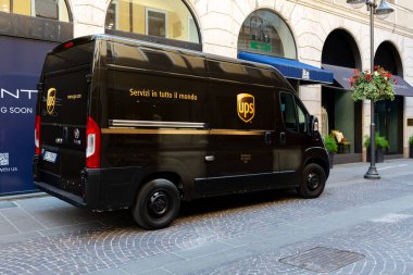 Padua, İtalya - 19 Haziran 2025: Güneşli bir yaz gününde lüks mağazaların yakınındaki işlek bir caddeye park edilmiş kargo kamyonu fotokopi alanı ile parlak siyah renkler sergiliyor