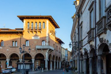 Montagnana, İtalya - 6 Nisan 2025: Büyüleyici sokak gösterileri, kemer ve balkonlu tarihi tuğla mimari, sıcak güneş ışığı altında yıkanmış, keşif için davetkar bir şehir atmosferi yaratıyor