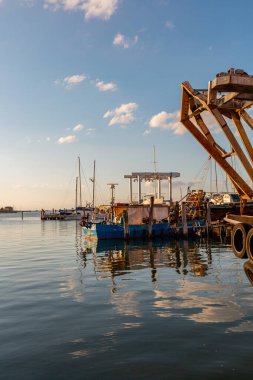 Ahşap direkler ve tekneyle güzel bir rıhtım manzarası, berrak mavi gökyüzünün altında sakin bir su yansıtıyor, huzurlu ve huzurlu bir ortam yaratıyor.