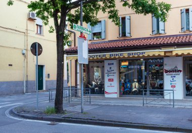 Sottomarina, İtalya - 25 Mayıs 2025: Sokak köşesindeki scooter dükkanında müşteriler için renkli tabelalar ve çeşitli scooterlar sergileniyor