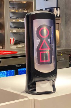 Padova, İtalya - 19 Haziran 2025: Modern bir restoran ortamında, canlı renkler ve çağdaş tasarım unsurları sergilenen, iSquid Game filminden ikonik şekiller içeren eşsiz kağıt dağıtıcısı