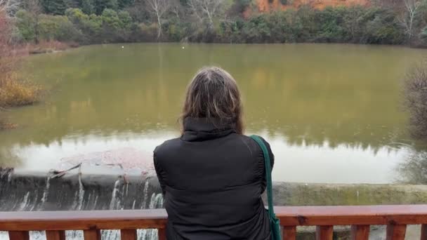 Barajın Yağmurun Kasvetli Kış Gününün Manzarasının Tadını Çıkaran Genç Kadın — Stok video