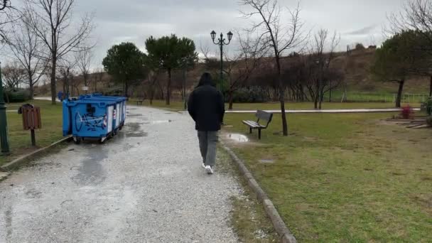 雨の中公園を歩く 雨の日を身に着けている男1 — ストック動画