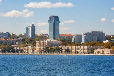 View to the shore of Bosforus strait on an early autumn day. Residential buildings and skyscrapers along the shore and Dolmabahce Palace in front of them.
