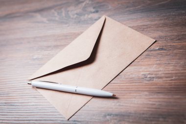 Masanın üzerinde kalem olan zarf.