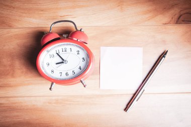 Masada alarm saati olan boş bir not kağıdı
