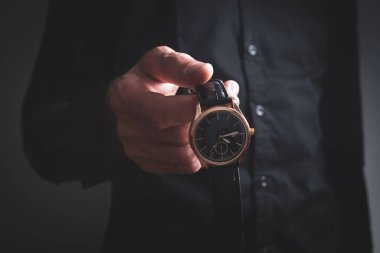 Genç adam kol saati takıyor.