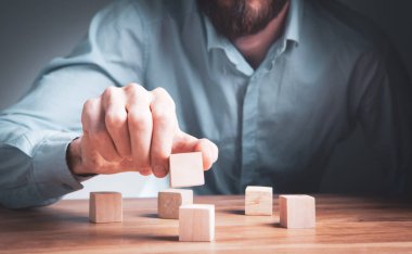 Ahşap küplerden bir yapı yapan bir iş adamının yakınlaşması. Bir iş konsepti inşa etmek.
