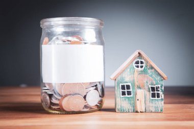 Bozuk paralı bir banka ve masanın üstünde bir ev.