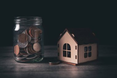 Bozuk paralı bir banka ve masanın üstünde bir ev.