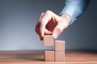 İş adamı eli, iş dünyasının ahşap bir figürünü tutuyor. Strateji kavramı.