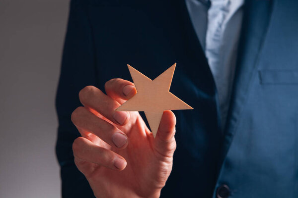 business man showing star on dark background. success concept