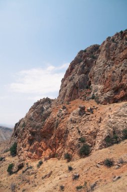 Bulutlu gökyüzünün altındaki tepelerin ortasındaki bir kayanın yüksek açılı görüntüsü.