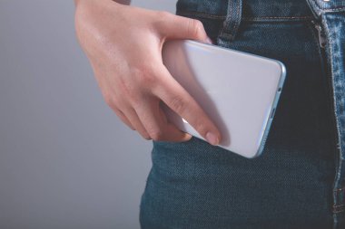 Gri arka planda cep telefonu tutan kadın..