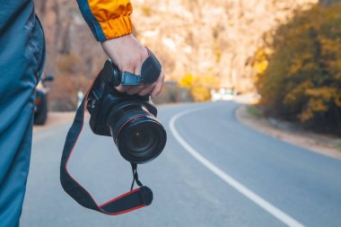 Fotoğrafçı, dağın arka planında kamerayla fotoğraf çekiyor.