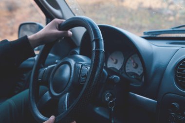 Direksiyon simidi kullanan bir sürücü..