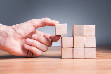 Beyaz arka plan, iş ve başarı konsepti üzerinde tahta blokları olan ahşap bloklar tutan bir adam..