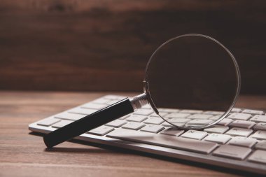 beyaz bilgisayar faresi ve bir masanın üzerinde büyüteç.