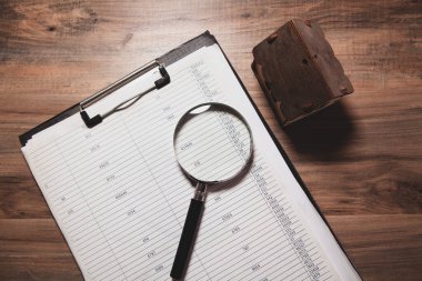 Tahta bir arka planda büyüteç, not defteri ve not defteri..