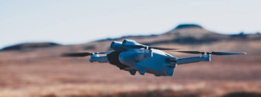 Bulutlu mavi gökyüzünde uçan İHA, boşluğu kopyala.