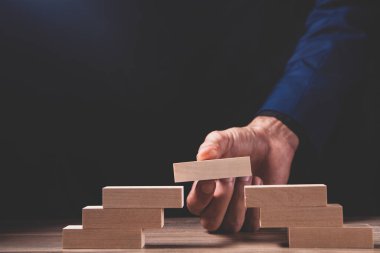 İş adamının eli ahşap masaya tahta bloklar koyuyor. iş konsepti ve stratejisi