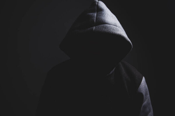 Человек в капюшоне в темной комнате, концепция ужаса