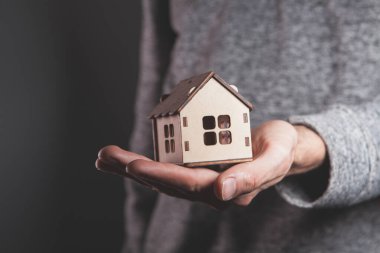 Evde elinde kahverengi karton bir model tutan bir adam var.